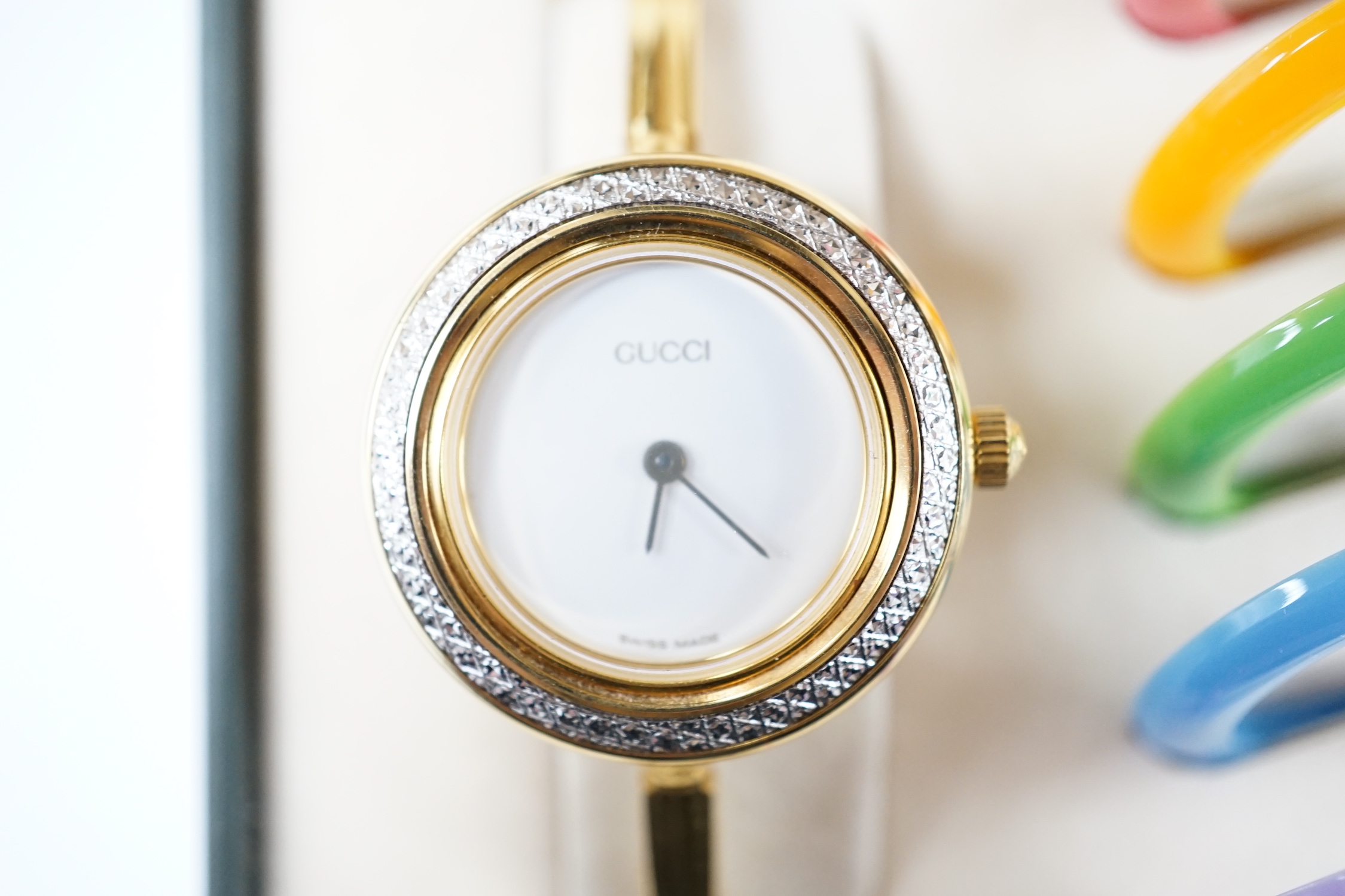 A lady's modern gilt Gucci quartz bangle wrist watch, with twelve interchangeable bezels, in original Gucci box.